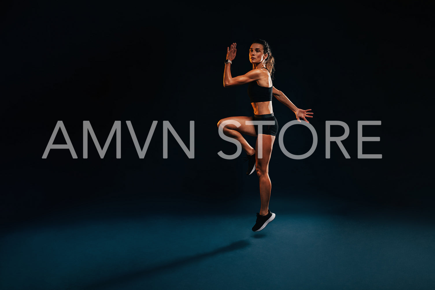 Female athlete jumping and stretching. Healthy woman exercising in studio warming up.