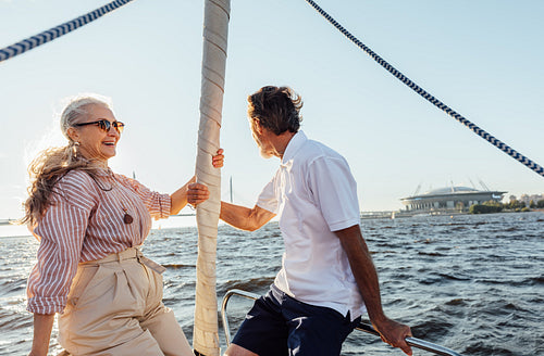 Romantic elderly couple sitting on a yacht bow and enjoying their summer journey