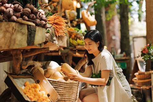 Woman holding a pumpkin. Smiling female shopping on a farmers market.