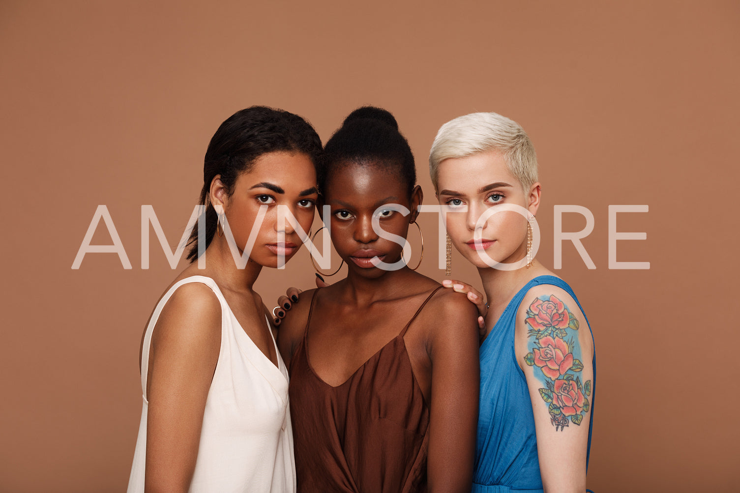 Group of three women of different races standing together against brown backdrop