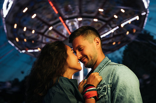 Young couple standing face to face at night in amusement park