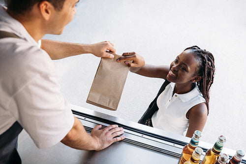 Woman receiving meal from a food truck in city. Young smiling female buying takeaway food.