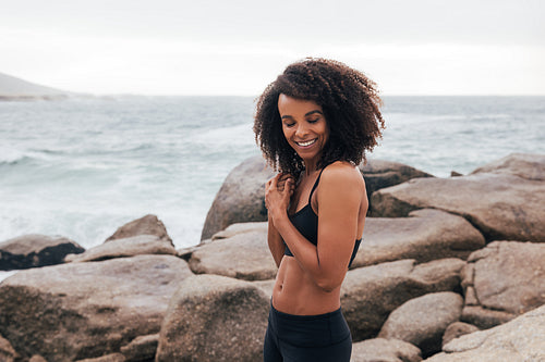 Happy woman in sportswear standing with closed eyes by ocean