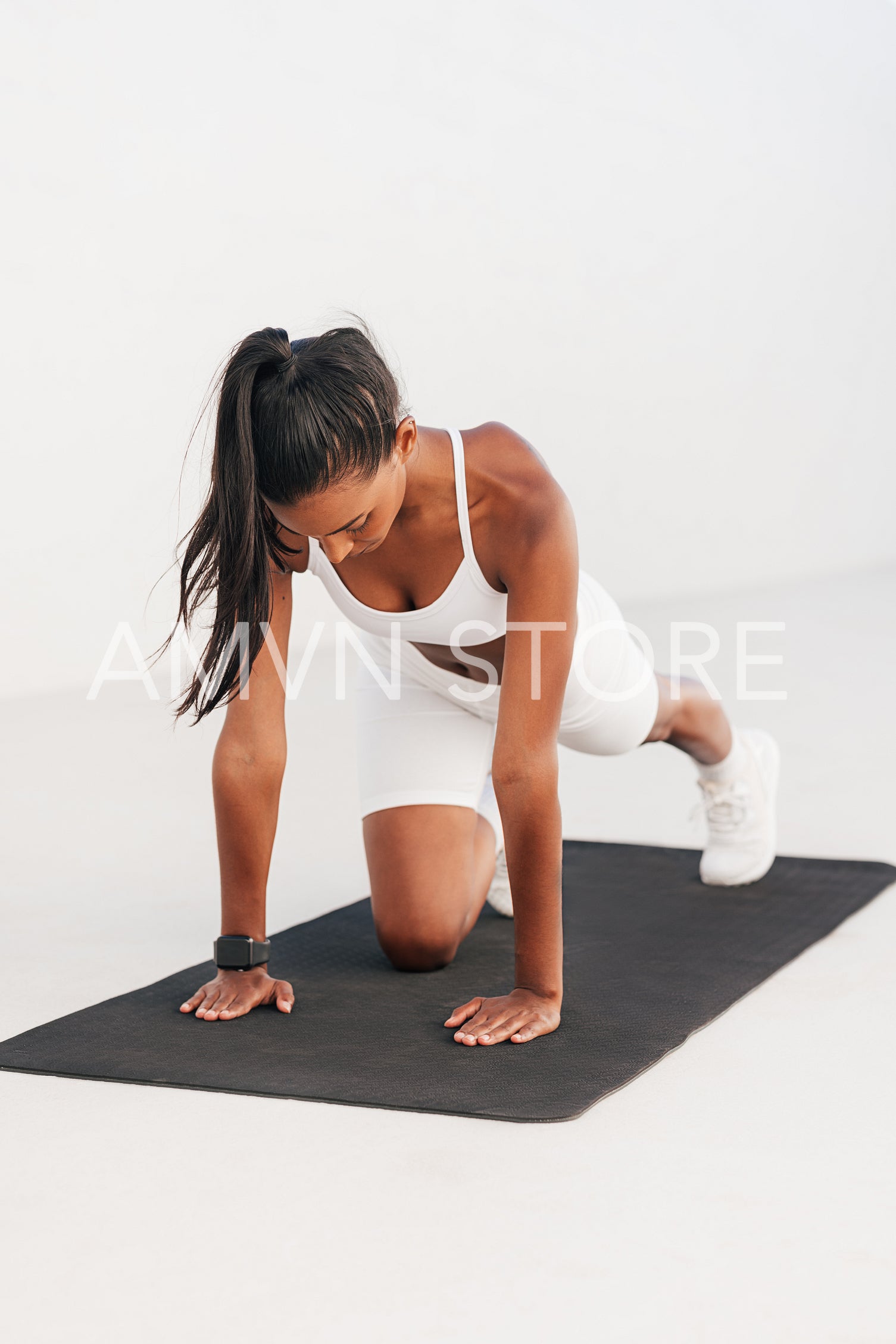 Slim female exercising on a mat. Full length of a young athlete warming up on a black mat.