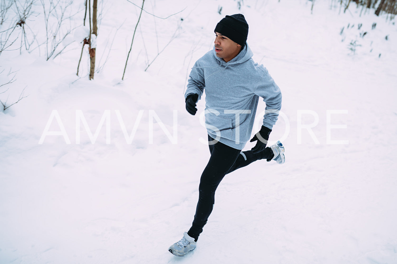 Top view of young man running in snow forest	
