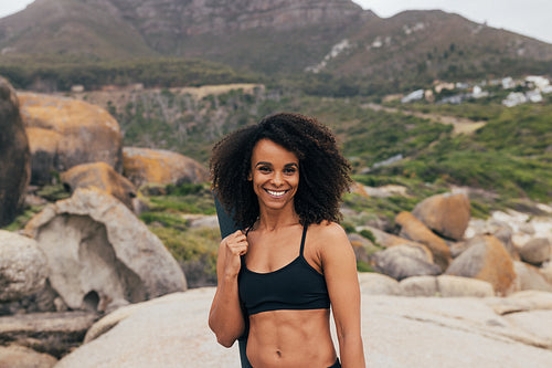 Portrait of a young beautiful woman with mat standing in park and smiling