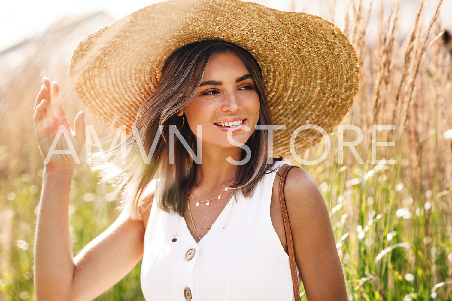 Young happy woman wearing big straw hat standing on the field	