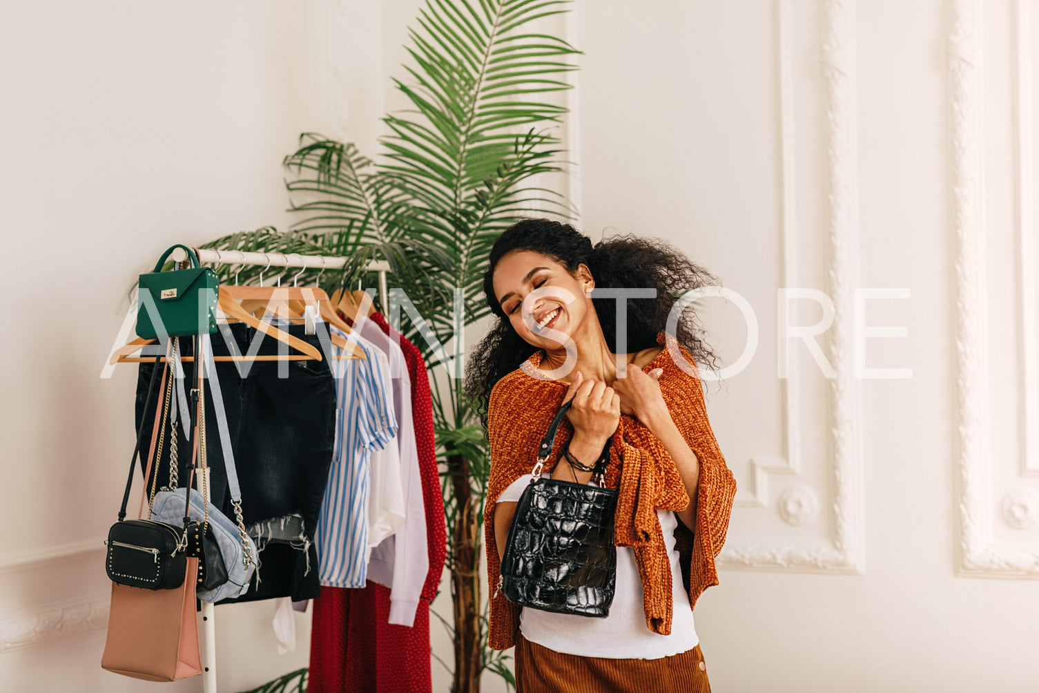 Smiling buyer with eyes closed standing at wardrobe	
