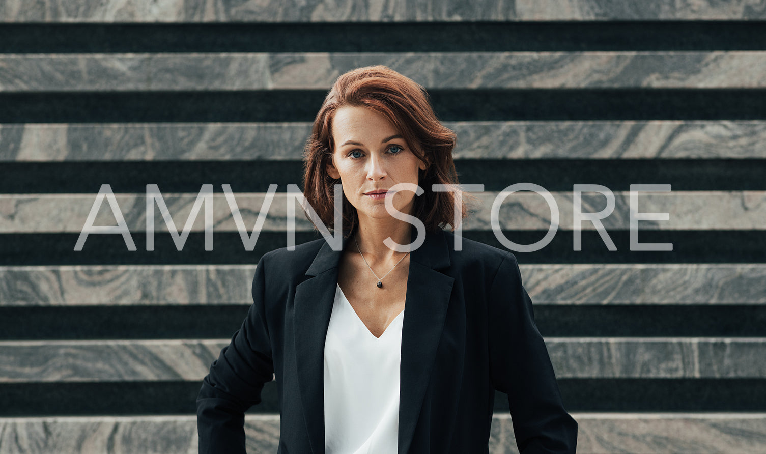 Portrait of a middle-aged female in black formal wear looking at camera. Confident businesswoman posing while standing outdoors.