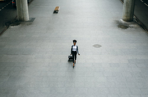 High angle view of young businesswoman walking on the sidewalk to a taxi