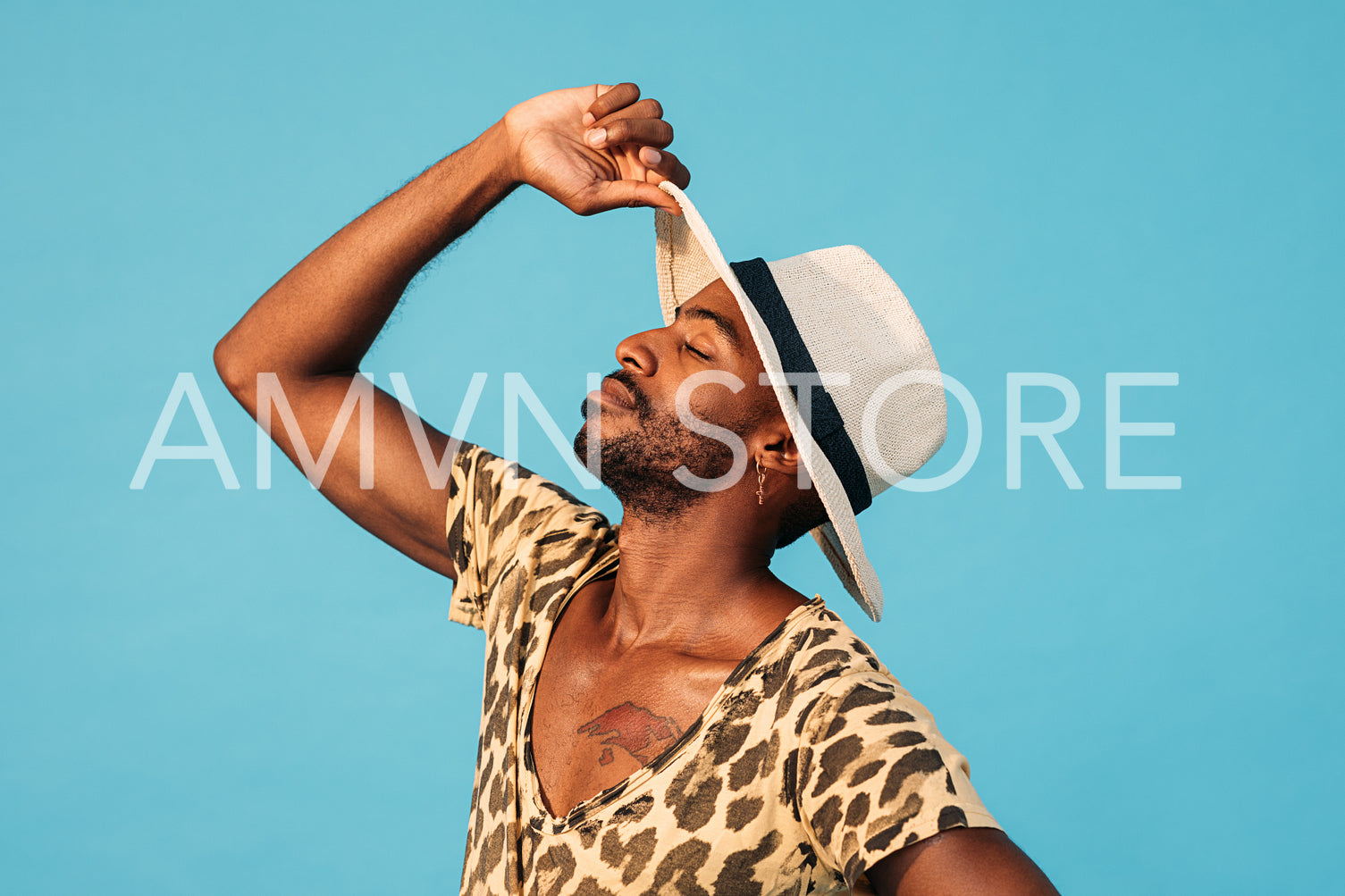 Side view of young stylish man with head up holding a straw hat with closed eyes