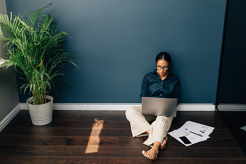 High angle view of businesswoman sitting on floor in living room. Young woman managing her online business from home.