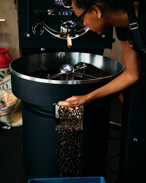 Woman working at roasting coffee machine