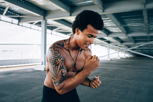 Male athlete with bare chest warming up before training