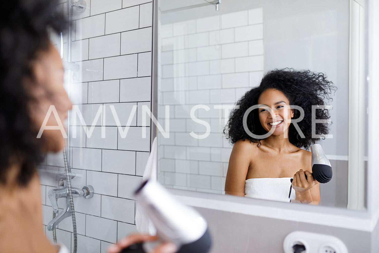 Smiling woman with hair dryer looking at mirror	