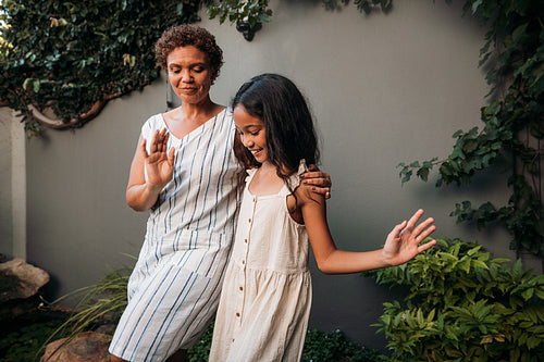 Granny and girl learning dance moves together on a backyard