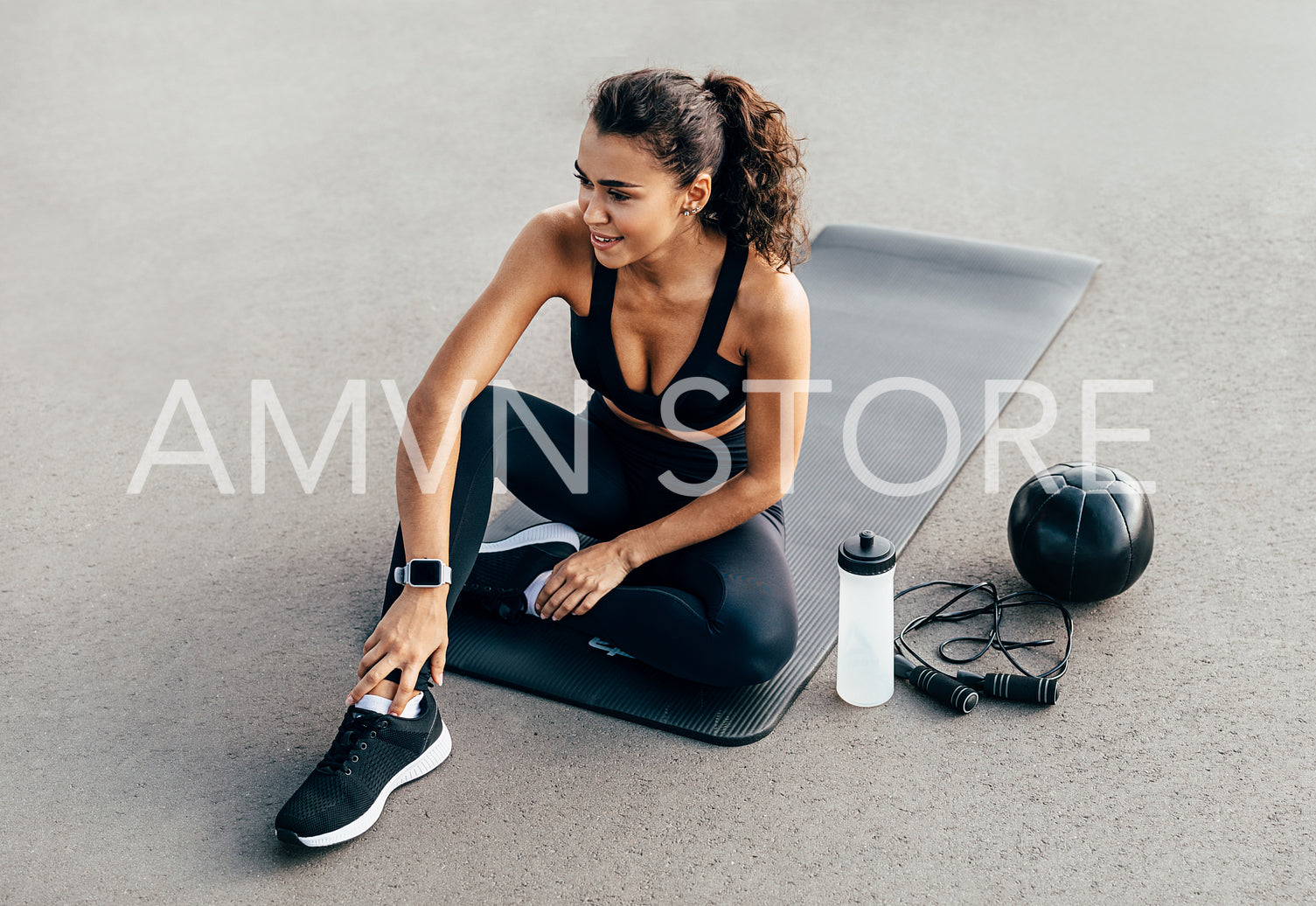 Beautiful female athlete looking away while sitting on mat outdoors	