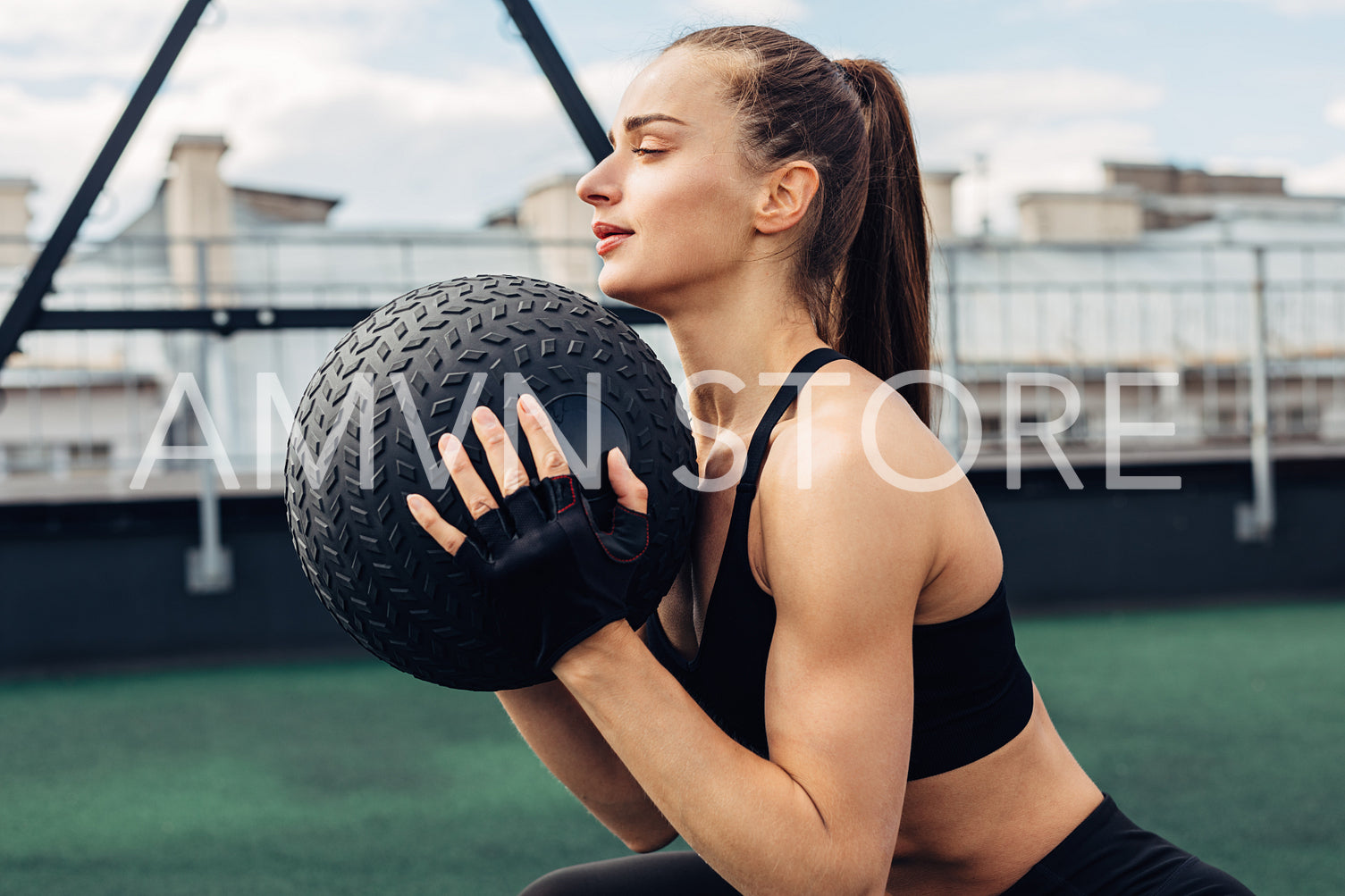 Woman holding medicine ball. Young athlete doing squats on rooftop.	
