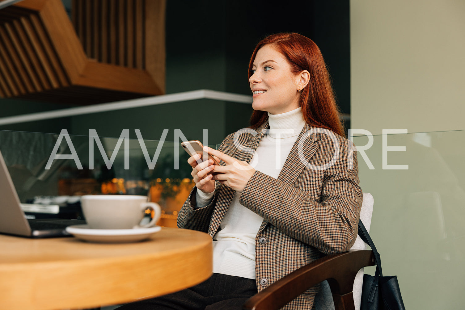 Businesswoman with ginger hair sitting in a cafe and using a smartphone