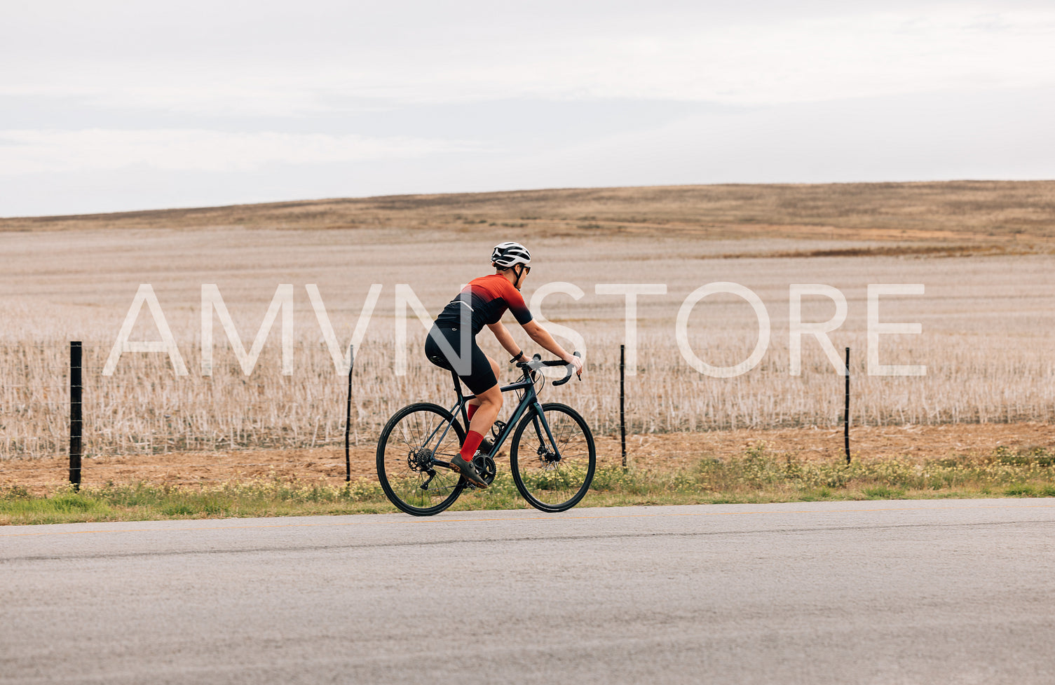 Side view of professional female cyclist riding pro bike against agriculture field