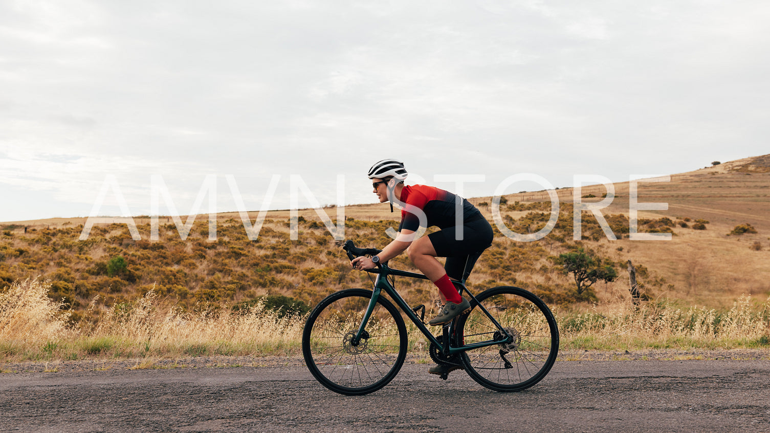 Side view of young woman cyclist riding on bicycle against hill