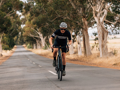 Professional female cyclist doing intense training on empty countryside road