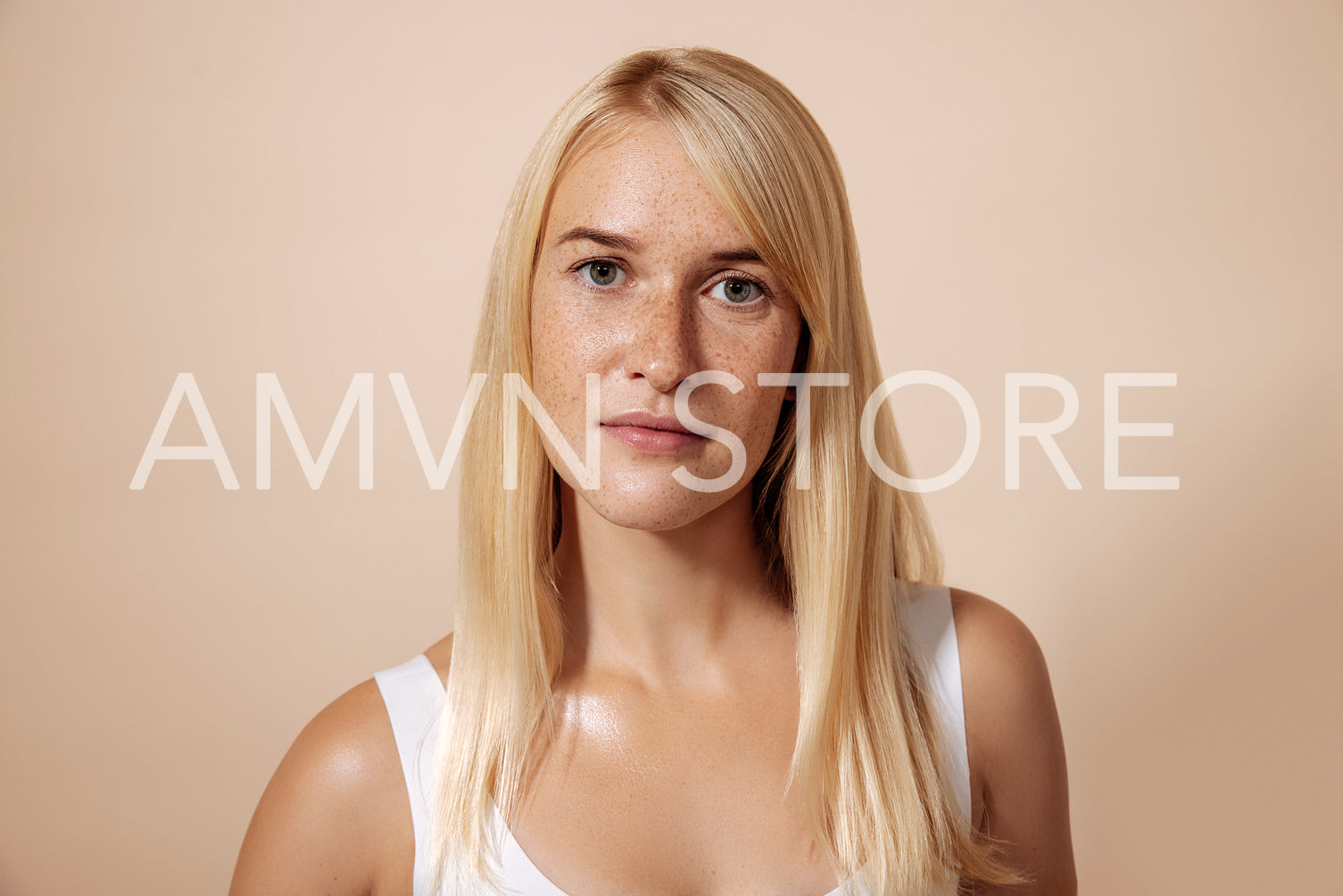 Portrait of young blond woman with freckles standing in a studio