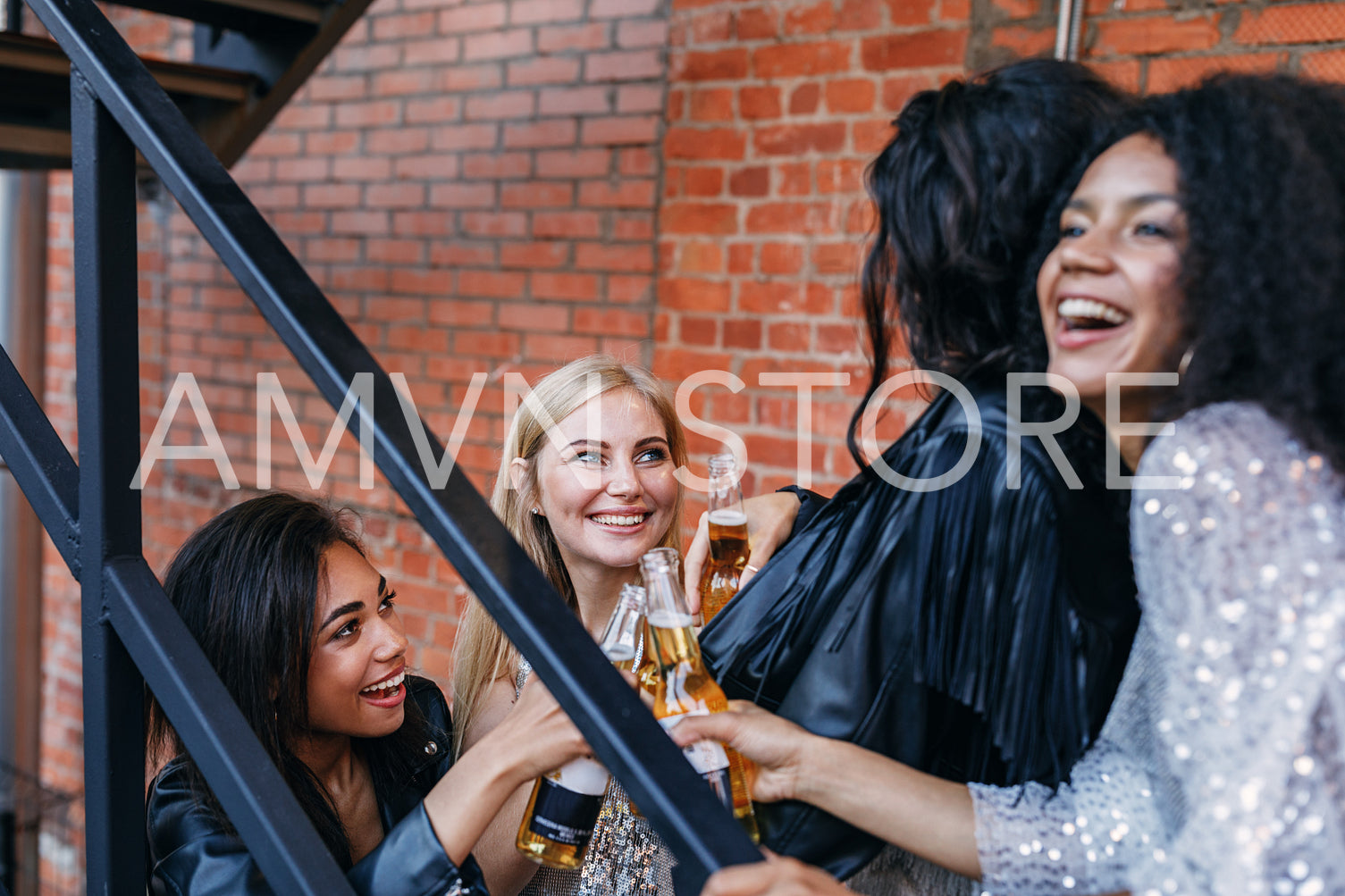 Multi-ethnic friends standing on the staircase with bottles of beer	