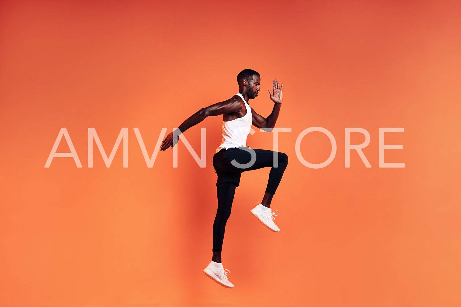 Fit man jumping in studio. Male runnner warming up before workout against orange background