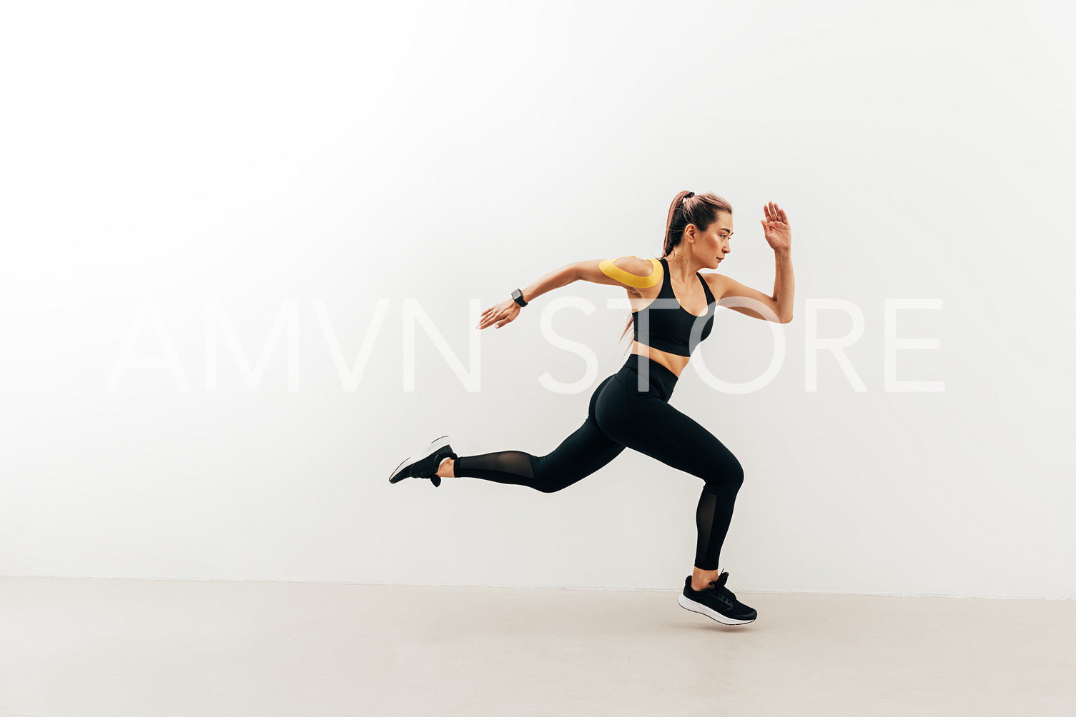 Side view of female athlete sprinting near a white wall