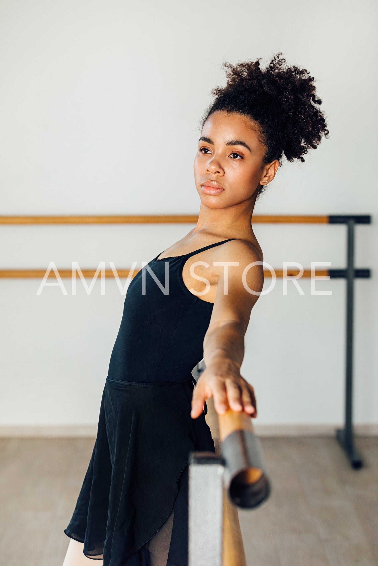 Young thoughtful woman looking away while leaning on barres at dance studio	