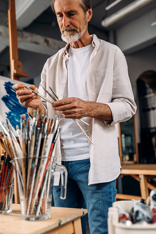 Male artist choosing paintbrushes in his studio