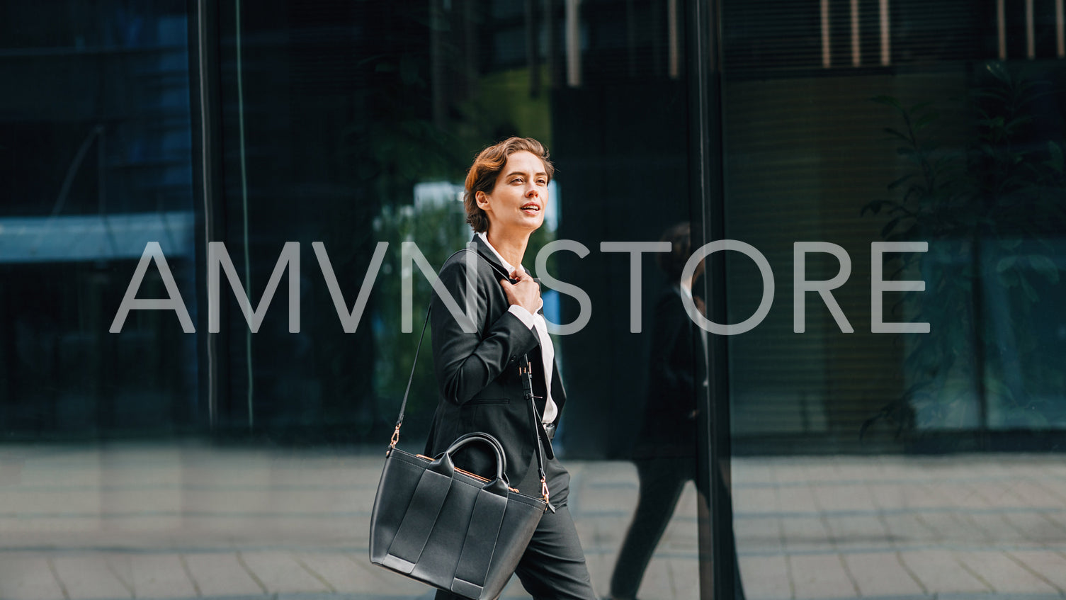 Side view of young businesswoman carrying a bag walking in front of an office building	