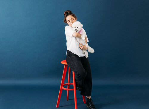 Woman in casuals sitting on chair in studio with her little fluf