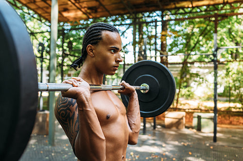 Male athlete preparing for deadlift exercise with weight bar on his chest