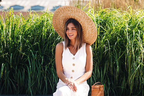 Young smiling woman sitting in the park and looking away