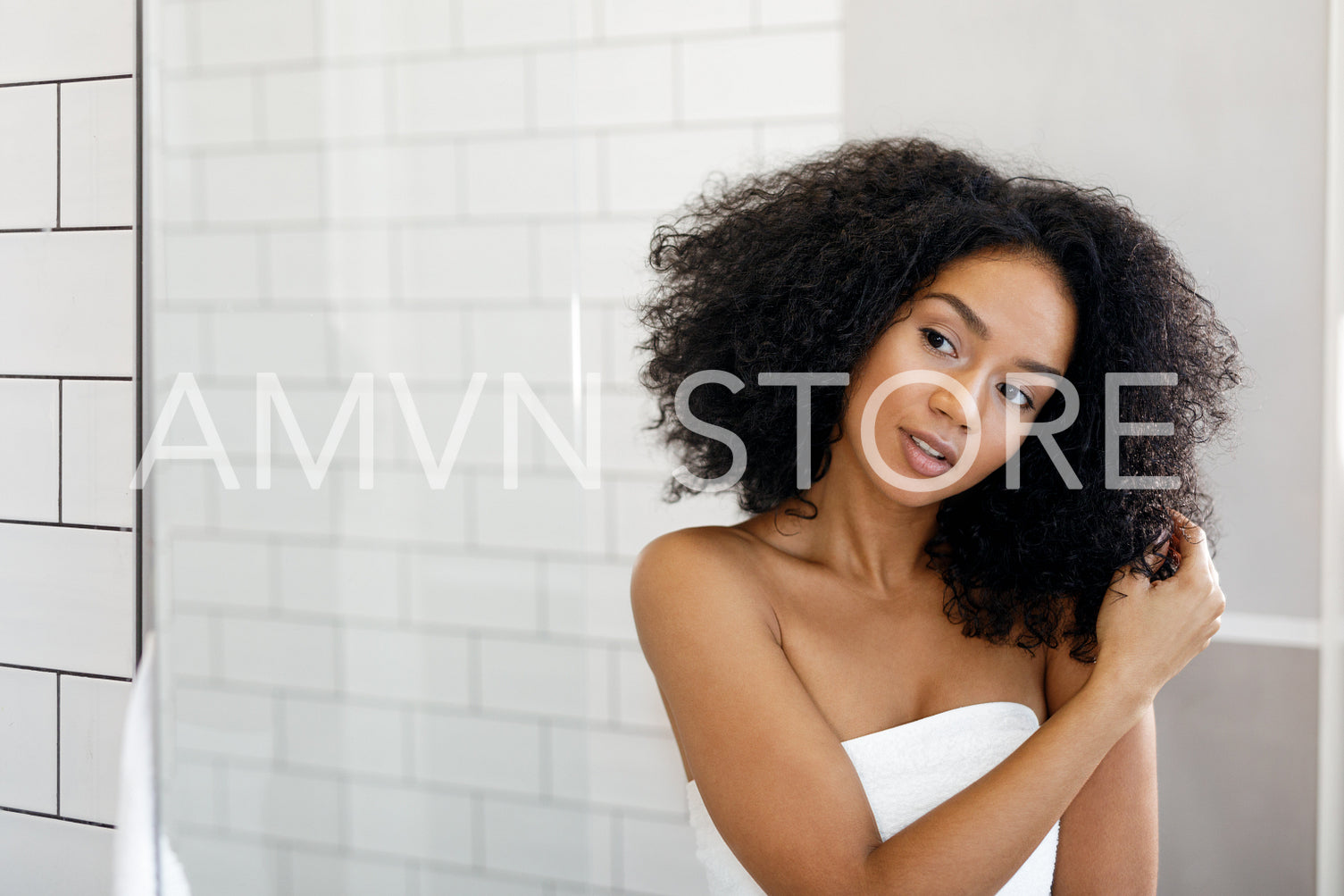 Beautiful woman observing her hair in mirror after bath, standing in front of mirror