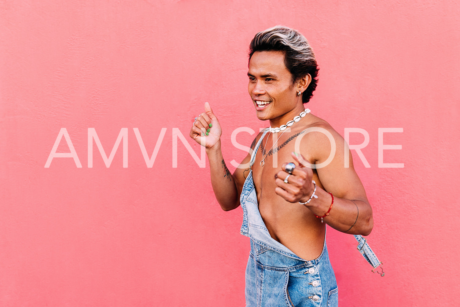 Young happy guy dancing against pink wall and looking away