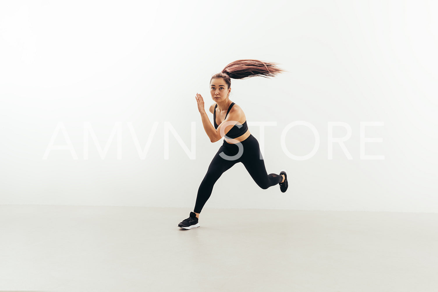 Front view of muscular woman running in studio against white wall