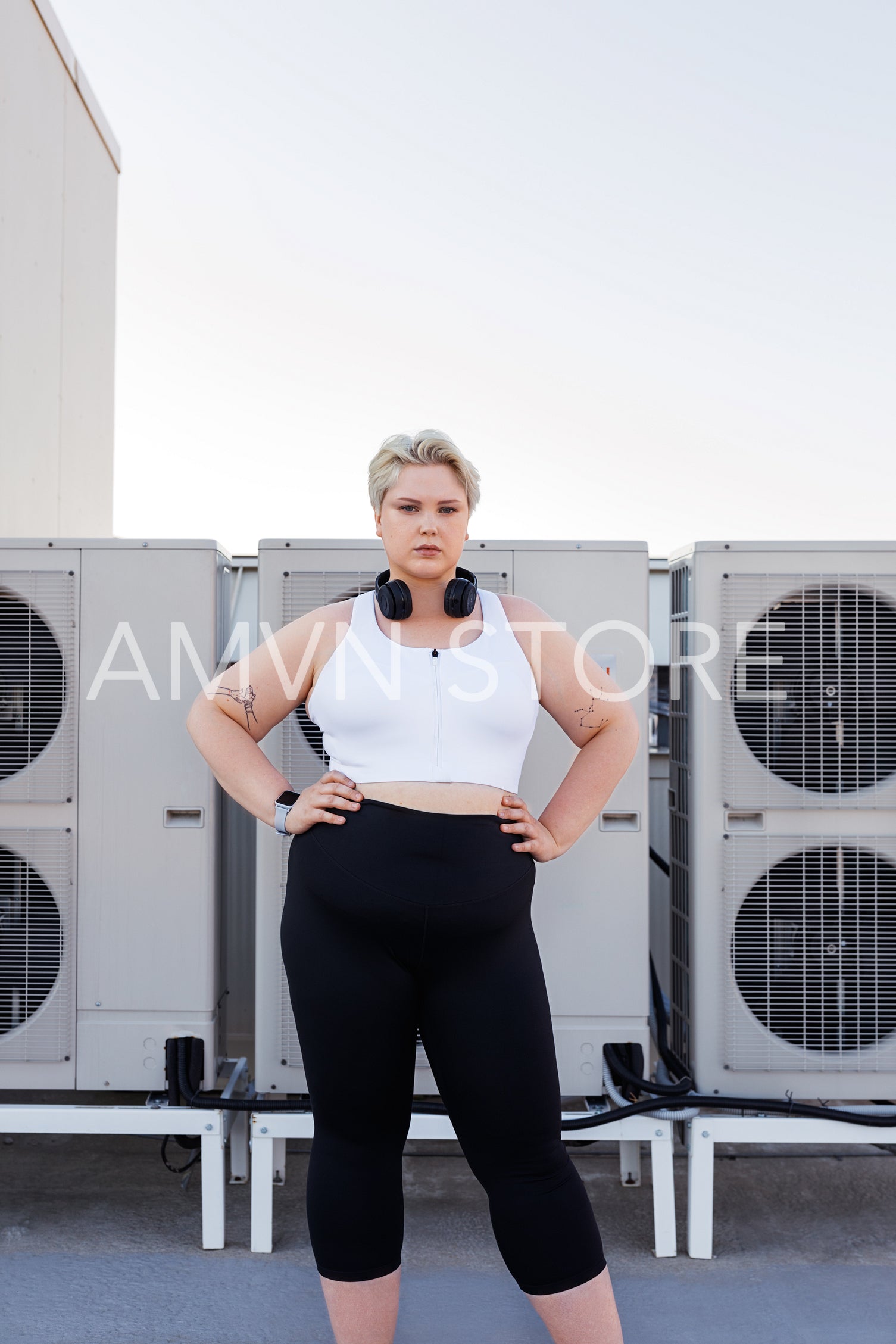 Confident plus size female in sportswear standing with her hands on hips	