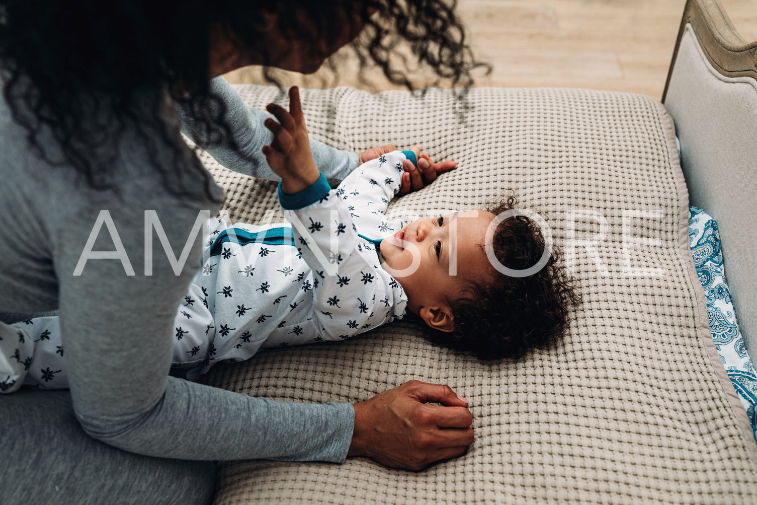 Baby boy lying on bed at home looking at mother	