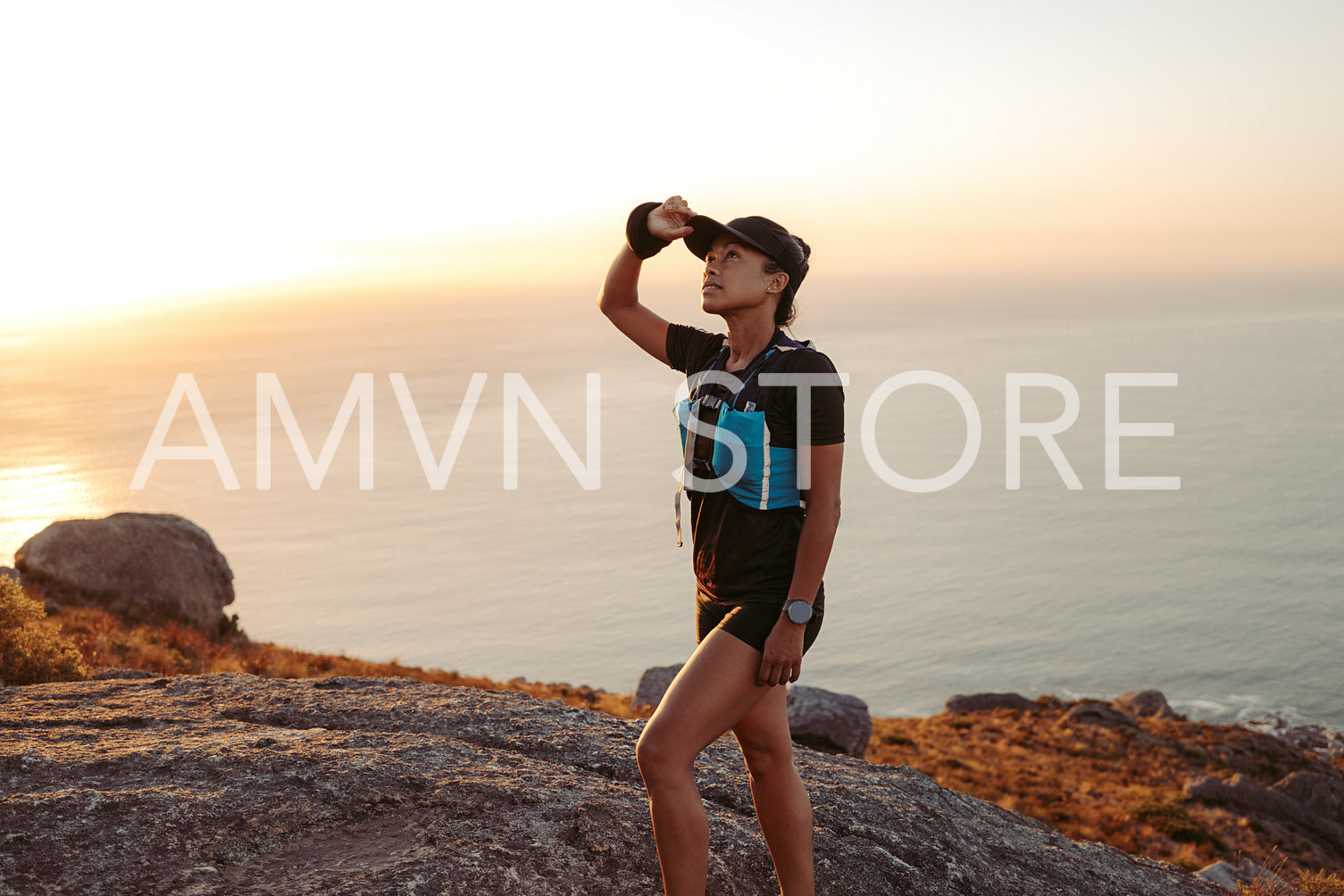 Woman trail runner holding a cap while walking up on a hill