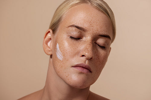 Close up portrait of beautiful caucasian woman with anti aging cream on face