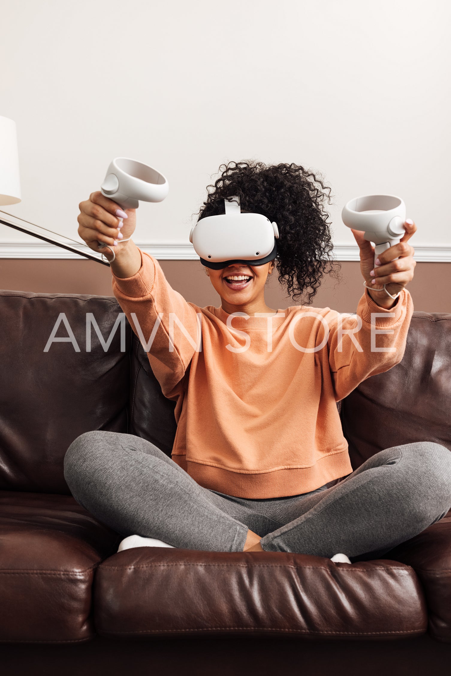 Young happy woman sitting on couch using VR set