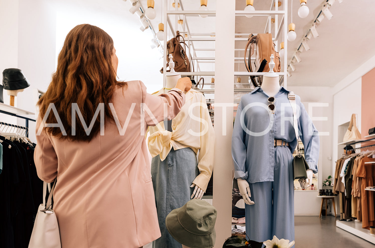 Back view of woman standing in small boutique and looking on a d