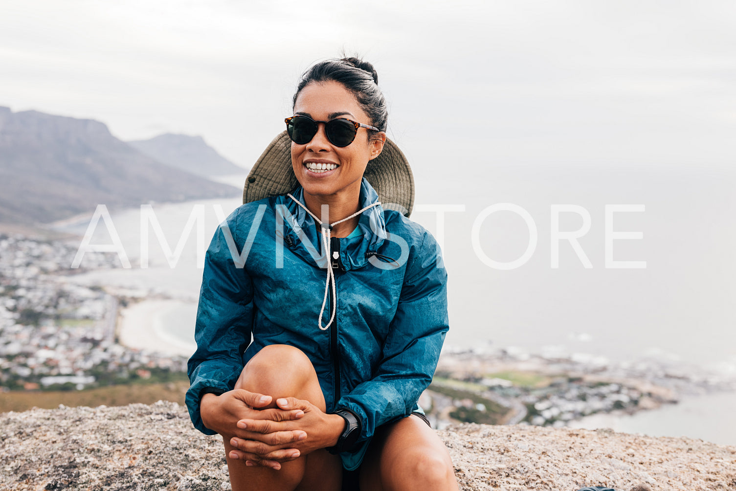 Smiling woman wearing sunglasses relaxing during hiking sitting on a rock