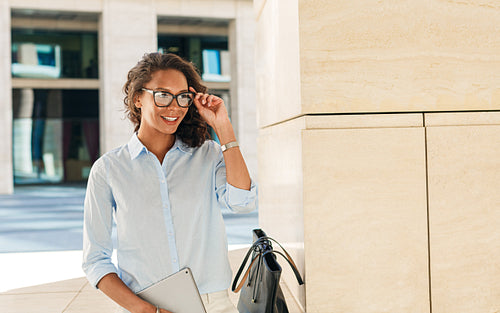 Smiling woman wearing eyeglasses holding digital tablet