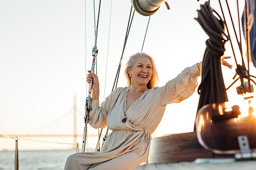 Happy senior woman sitting on a private yacht and pointing way