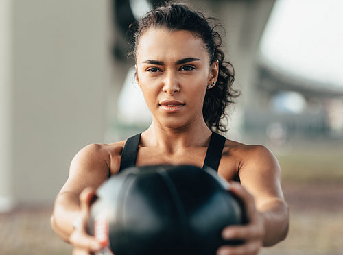 Muscular sportswoman doing exercise with a medicine ball outdoors