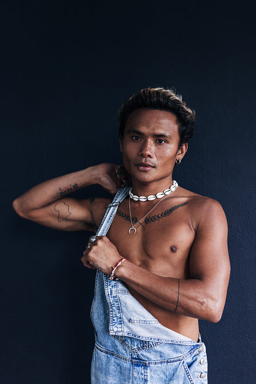 Portrait of a young male wearing overall standing at blue wall